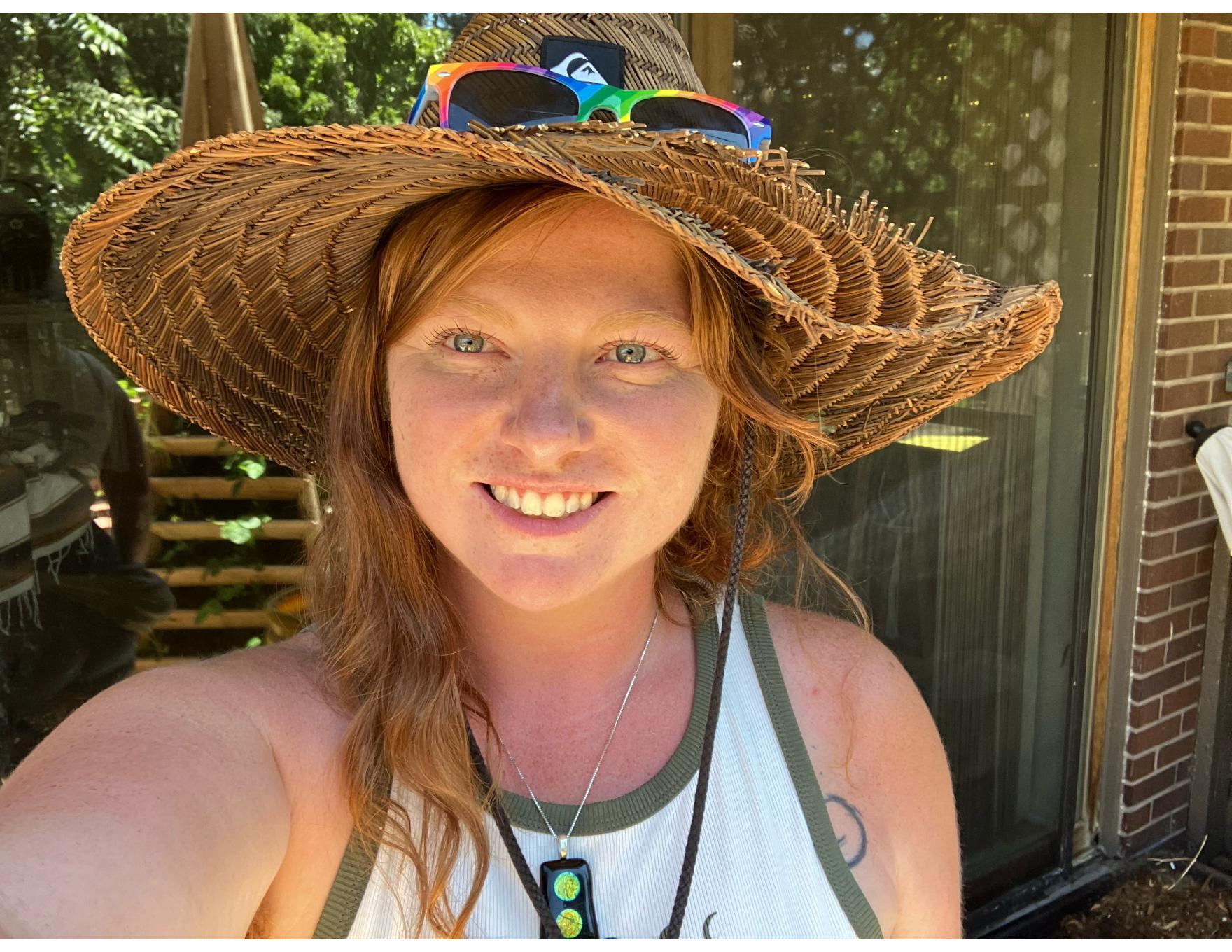 Avery, the grower behind Restin’ Peas, smiling in a woven sunhat